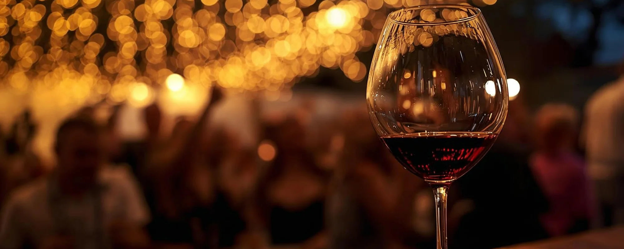 Weinglas mit Rotwein vor golden beleuchtetem Lichterhimmel beim Bardolino Weinfest