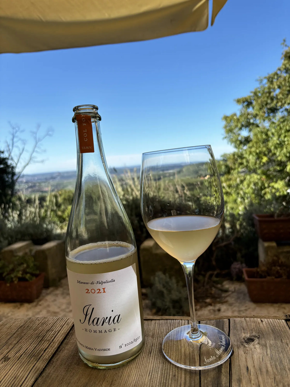 Flasche Ilaria Hommage 2021 von Tenuta Santa Maria Valverde mit Weinglas auf einer Terrasse in Marano di Valpolicella